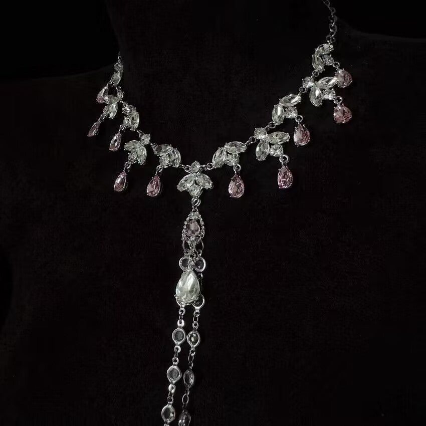 Close-up detail of silver crystal choker necklace with dangling pink drop crystals.