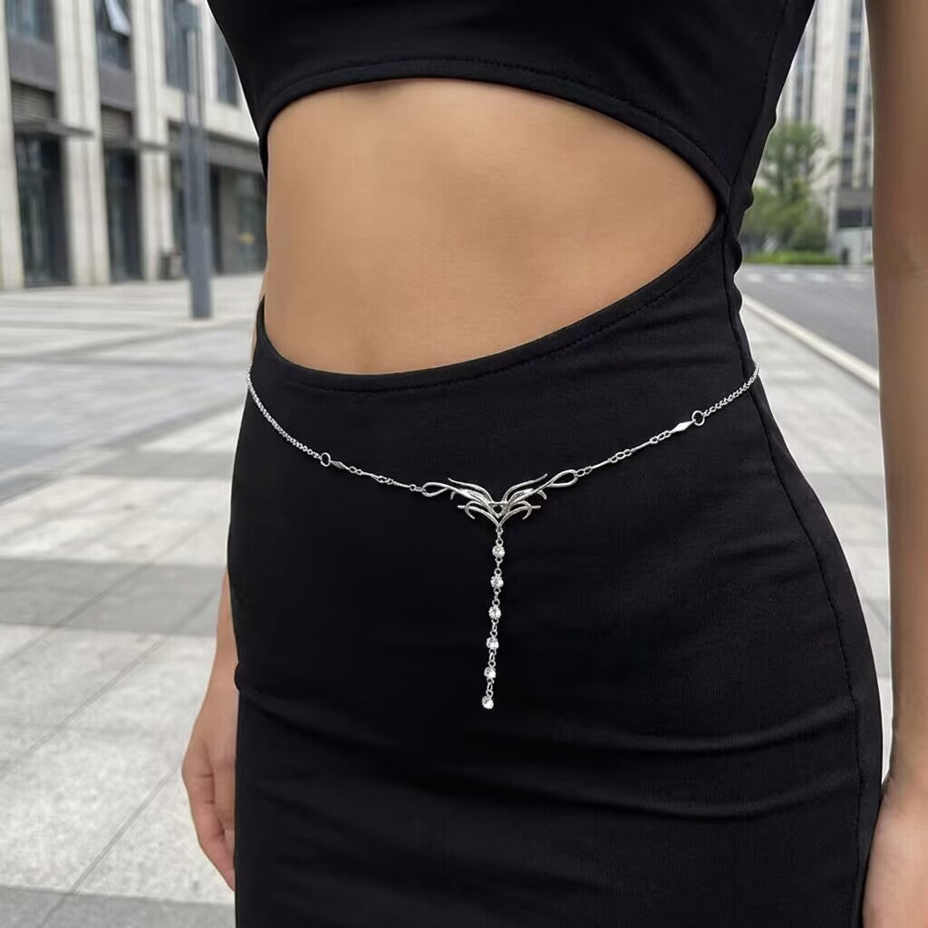 Y2K silver belly chain layered over a bodycon black cutout dress for street style