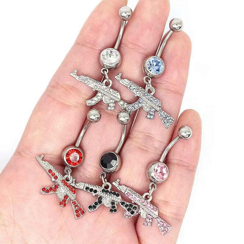 A hand holding five iced out gun belly rings with sparkling multi-colored rhinestones showing real-life scale.