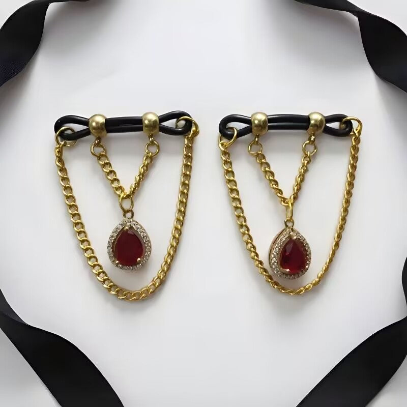 Dangle nipple clamps with ruby red teardrop gem pendants encircled by CZ stones and gold layered chains.