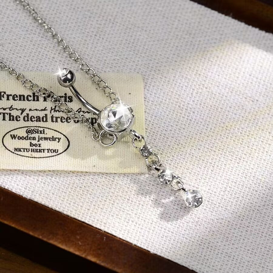 Dazzling cubic zirconia crystal belly ring connected to waist chain on neutral background.