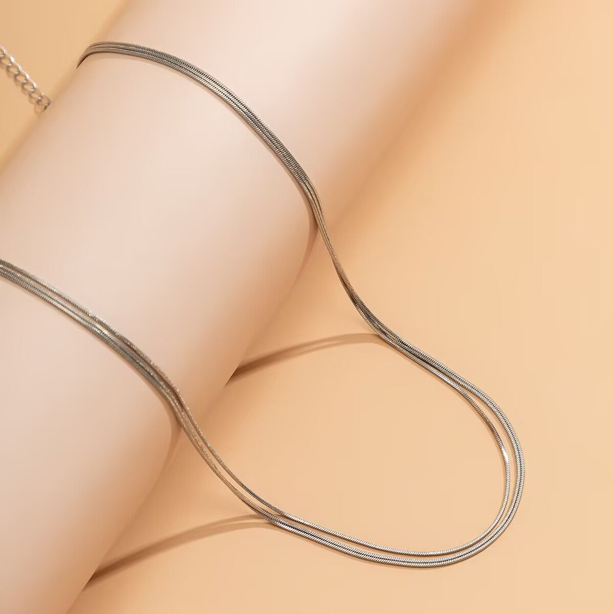 Close-up of a double-layered silver snake chain waist jewelry displayed on a cylindrical prop.