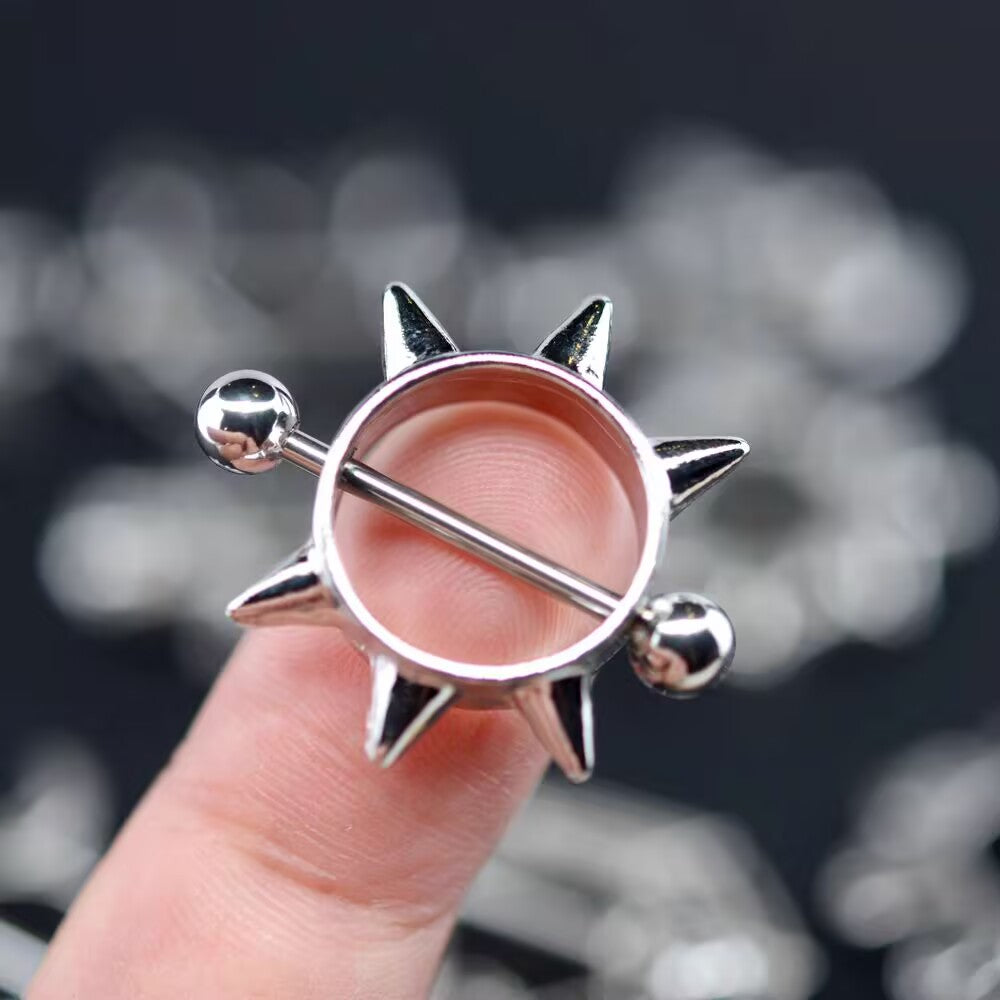 Close-up of a spiked nipple ring held on a finger for size perspective.