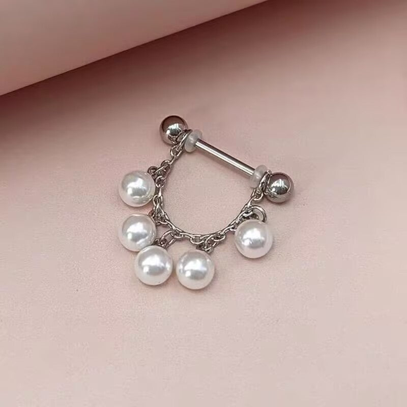 Chic pearl dangle chain nipple ring resting on a soft pink background for feminine body jewelry styling