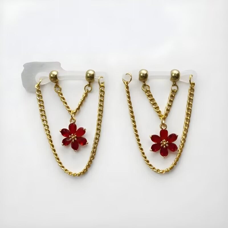 Fake nipple rings with red crystal flower pendants suspended on gold double chains with clear flexible loops.