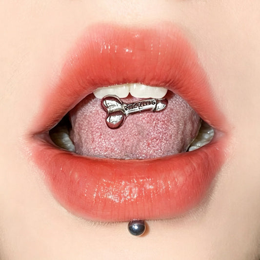 A person wearing a novelty penis-shaped tongue ring with an engraved suck me quote on the top barbell end.