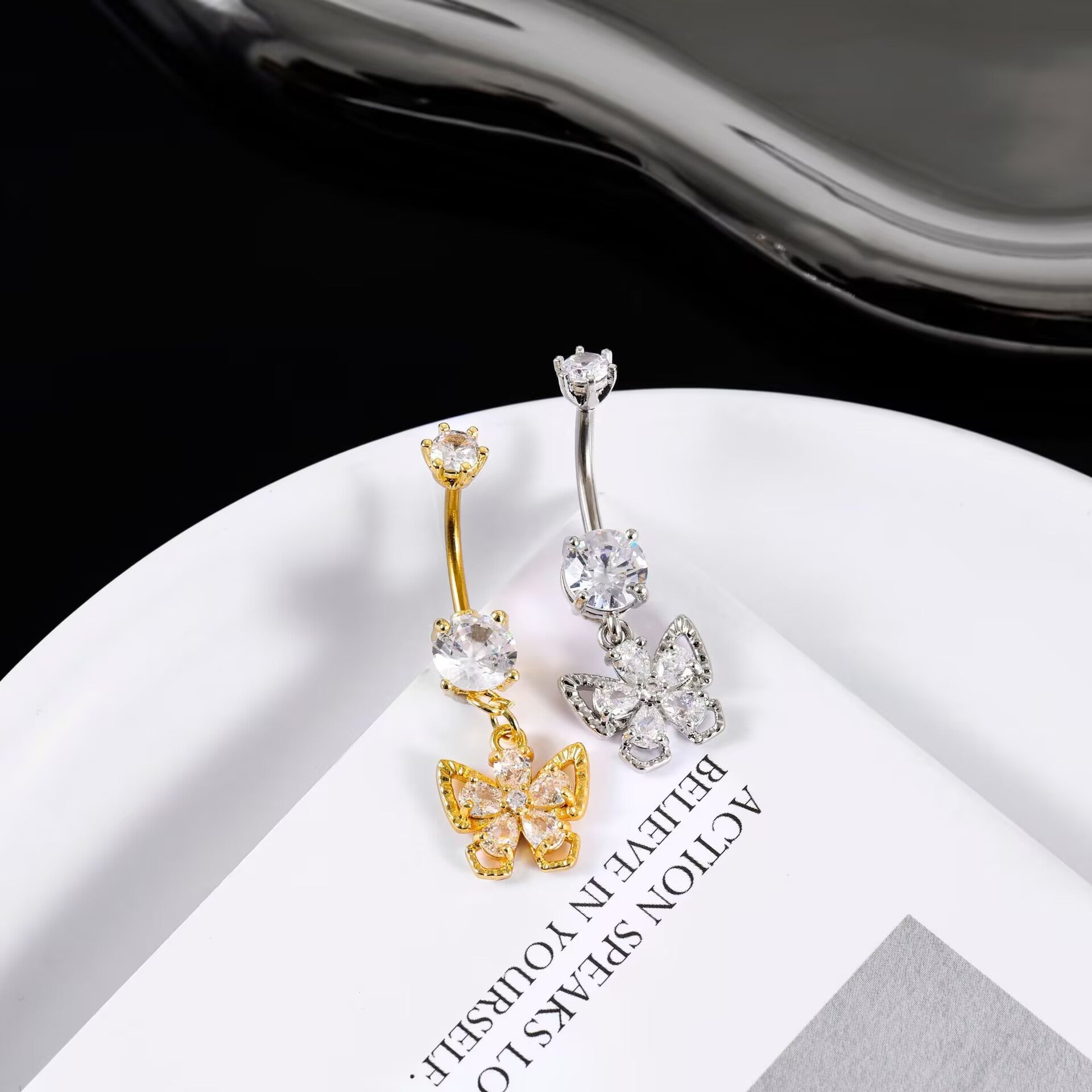 Luxury gold and premium silver butterfly dangling belly button rings styled together on a white aesthetic plate.