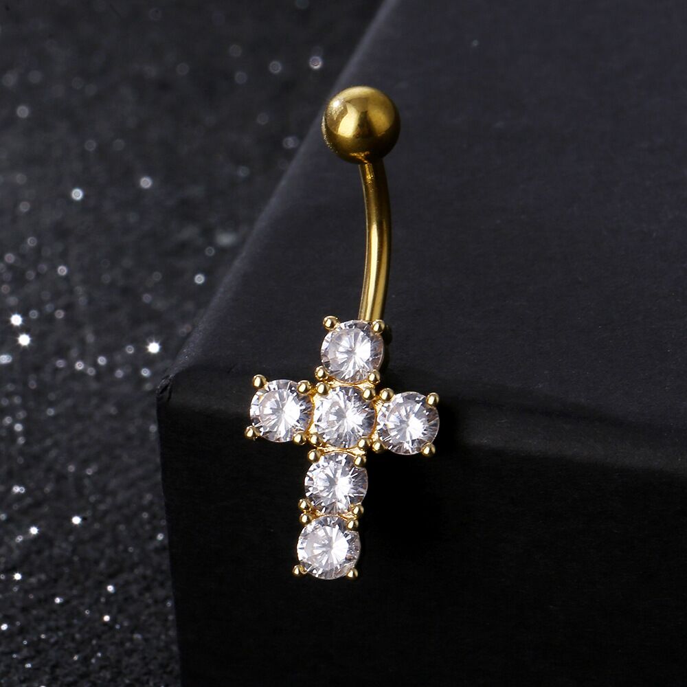 Elegant gold CZ crystal cross belly ring resting on black jewelry display box.