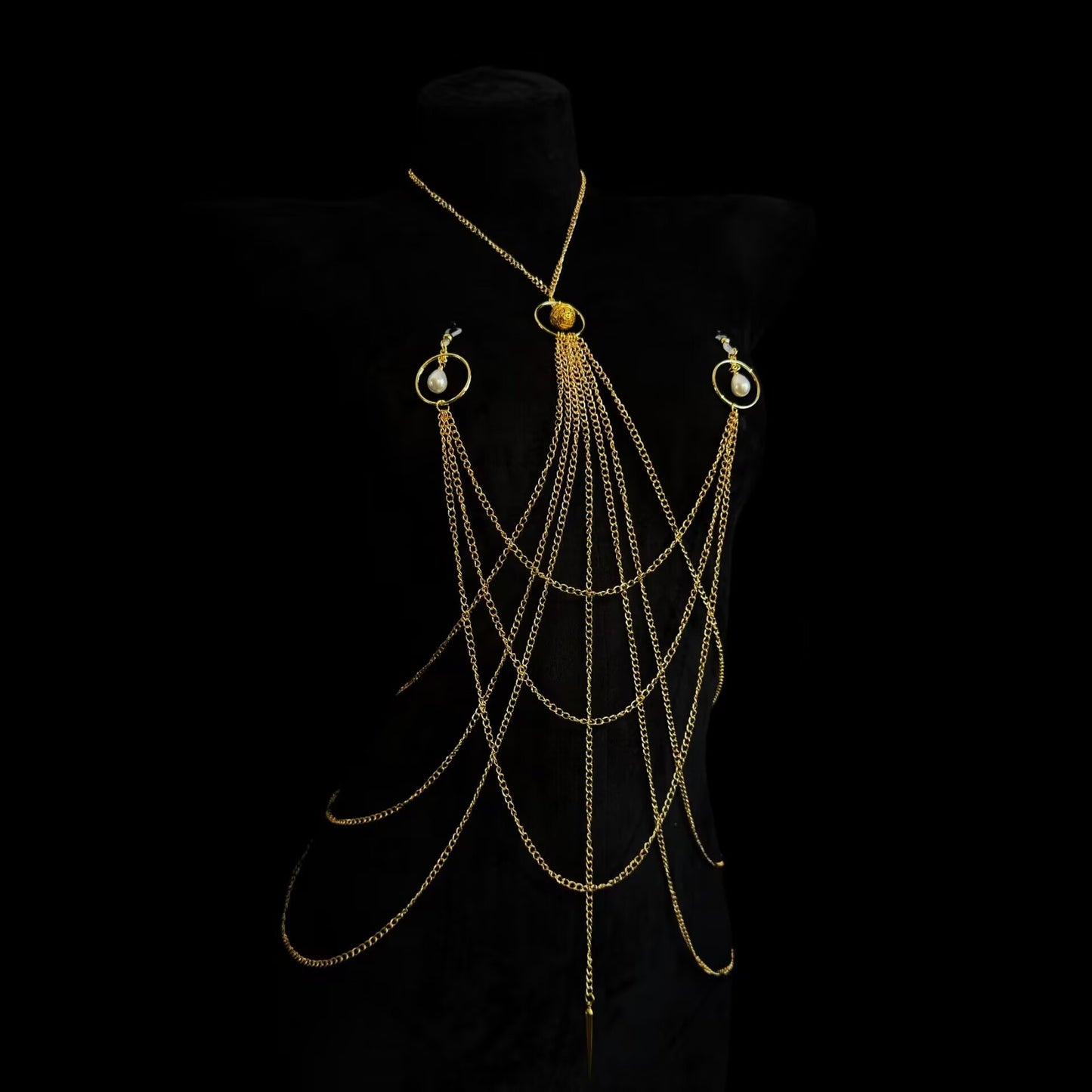 Gold layered body chain harness with non-pierced pearl ring nipple accents shown on black mannequin