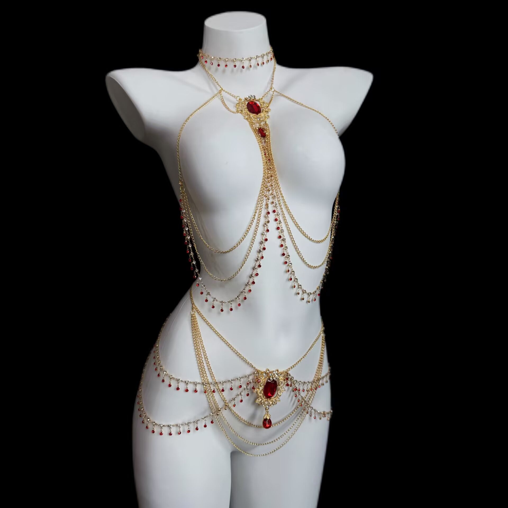Gold multi-layer chest body chain and ornate waist jewelry with crimson rhinestones and dangling beads worn on a white mannequin torso.