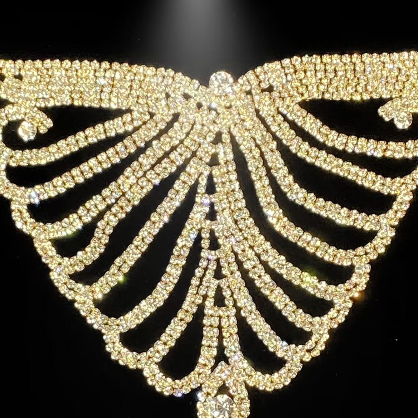 Close-up texture of gold rhinestone butterfly belly chain for rave and festival fashion.