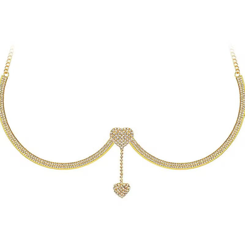 Gold rhinestone underwire breast chain bracket with dangling heart crystal accent on white background.