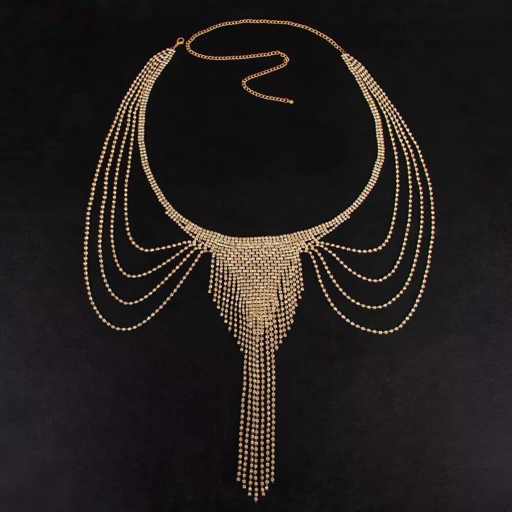 Gold rhinestone waist chain and belly harness laid flat on a dark background showing the cascading crystal tassel and adjustable waist loop.