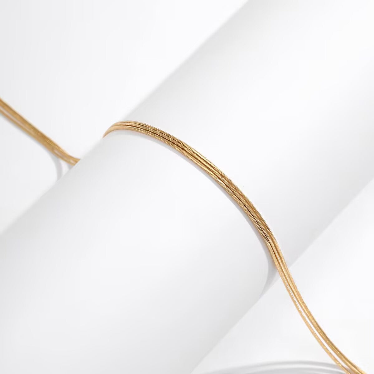 Extreme close-up detail showing the high-polish texture of multi-layered gold snake chain links.