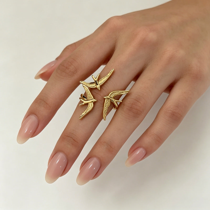 One gold three-swallow ring worn on an extended hand, showing the raised bird arrangement.