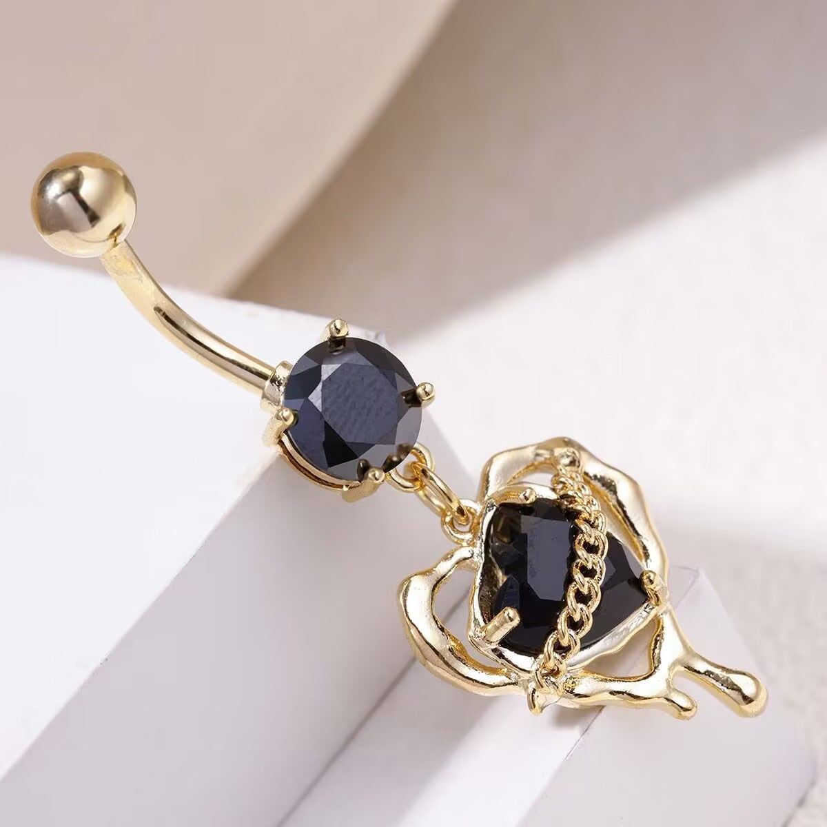 Close up of gold whimsigoth black heart dangle belly piercing jewelry with dripping molten effect