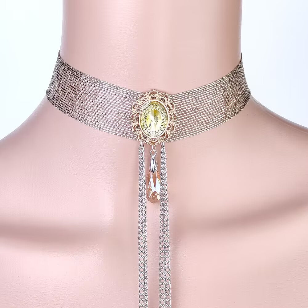 Close-up of a gold woven mesh choker collar with an oval yellow crystal pendant and dangling teardrop gem.