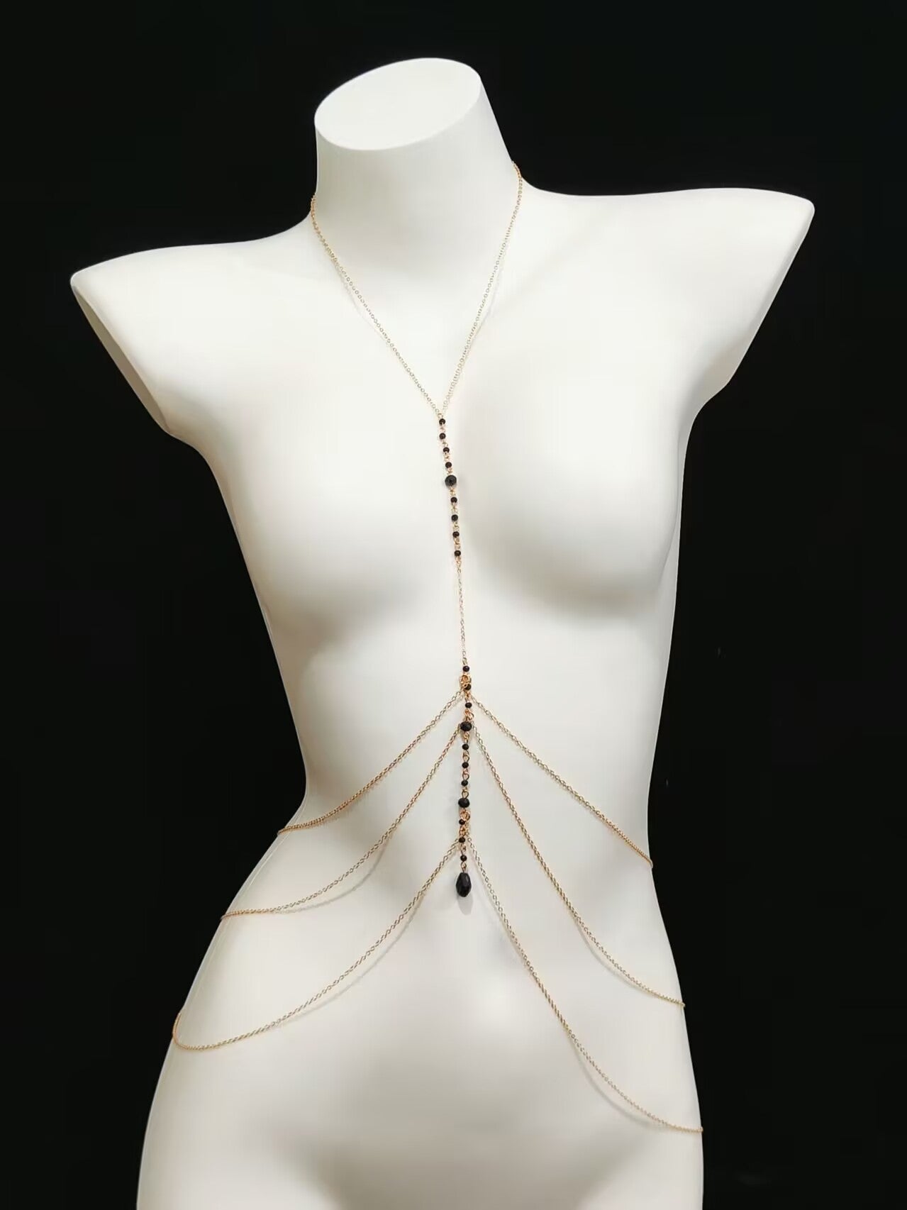 Gold Y-necklace layered waist harness chain shown on a white mannequin with a black background.