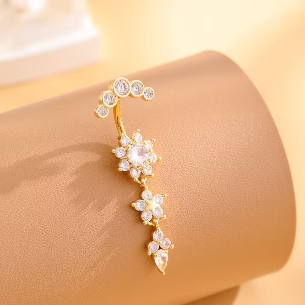 Gold zircon flower dangle belly button ring elegantly displayed showing warm tone finish and sparkling CZ.