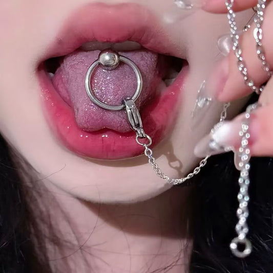 Front view of an alt coquette style tongue piercing showing the under-tongue ball and the silver chain draping down from the top O-ring.