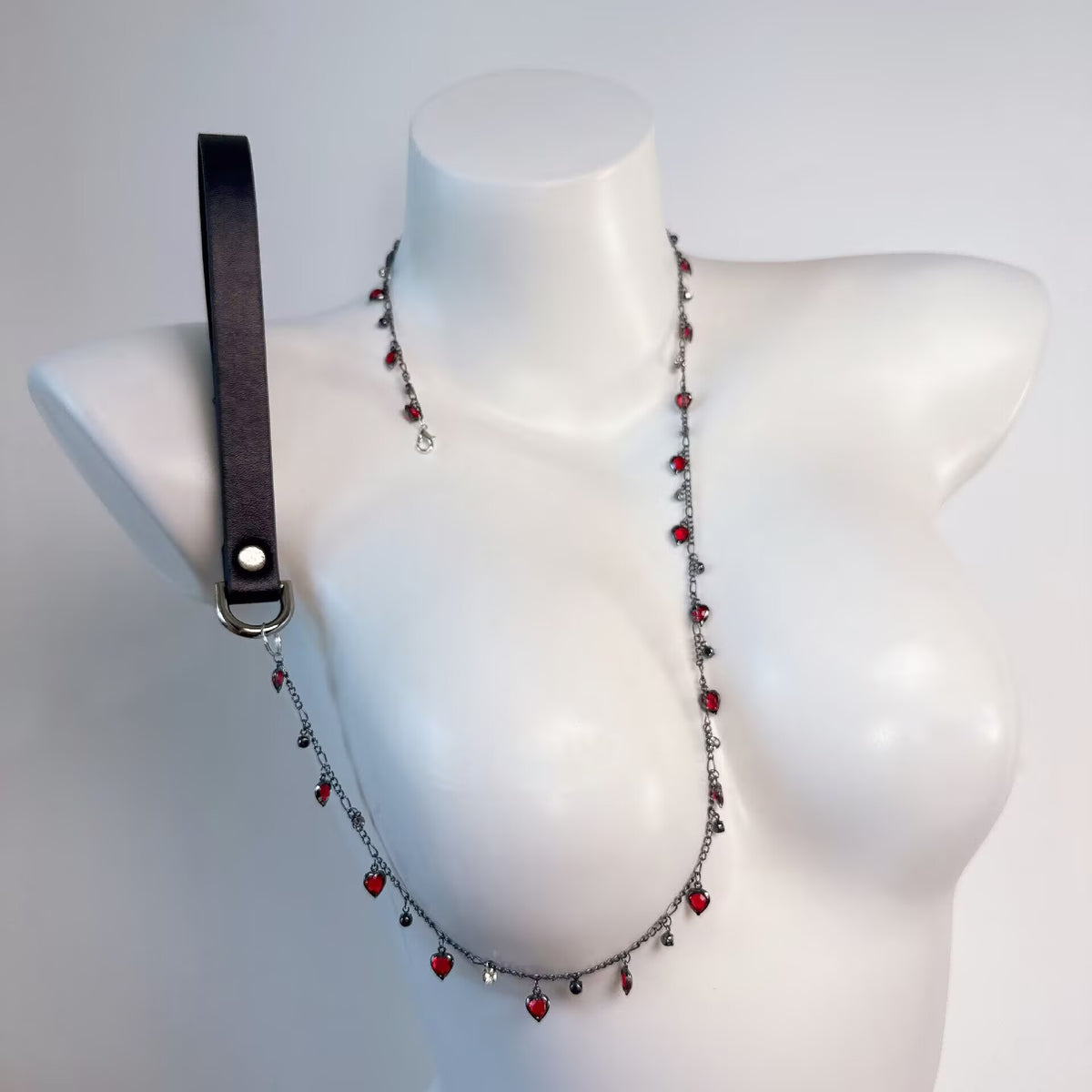 Long gothic body harness chain with dangling red crystal hearts connected to a leatherette handle leash