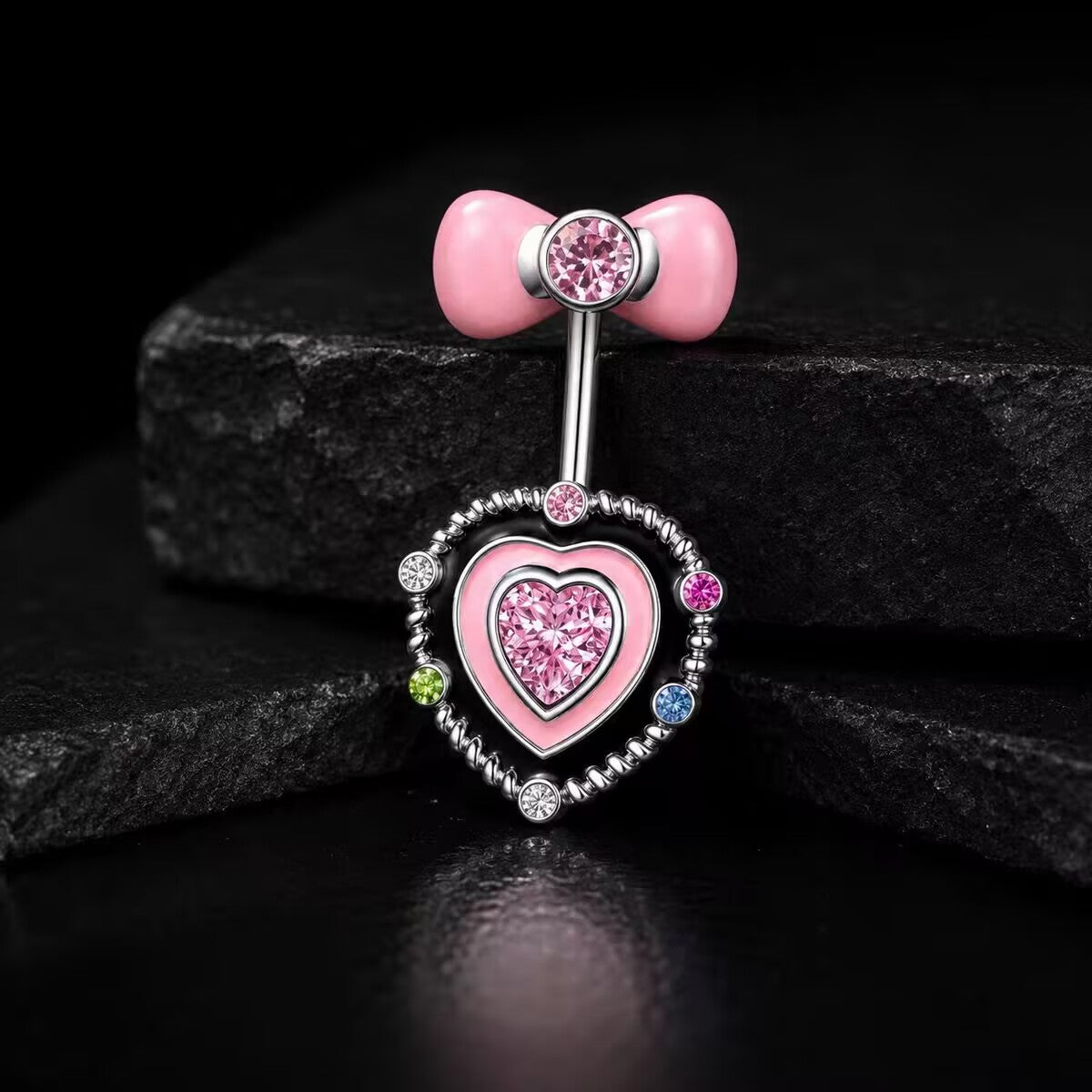 Studio product shot of a gothic pink CZ bow belly ring displayed on black stone background highlighting the shiny enamel contrast.