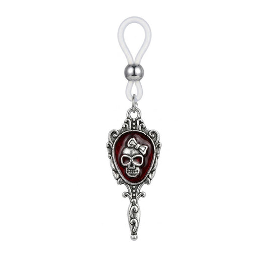 A single silver gothic nipple ring featuring a skull with a bow inside a vintage mirror frame with an adjustable silicone loop.
