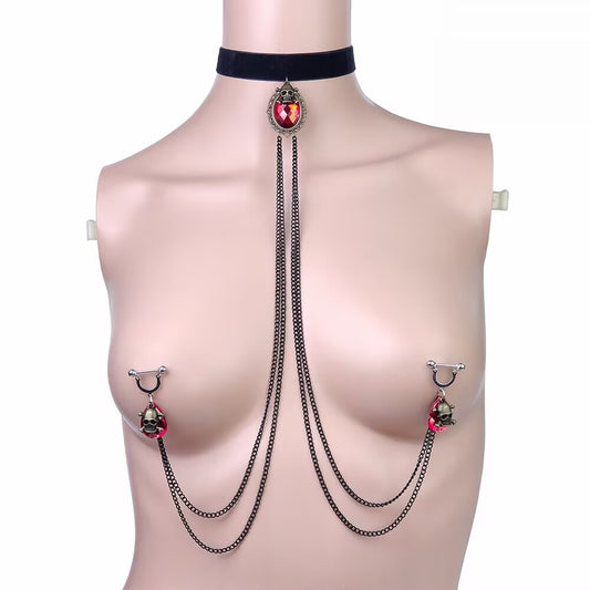 Gothic red crystal teardrop choker connected with chains to red skull nipple rings on mannequin.