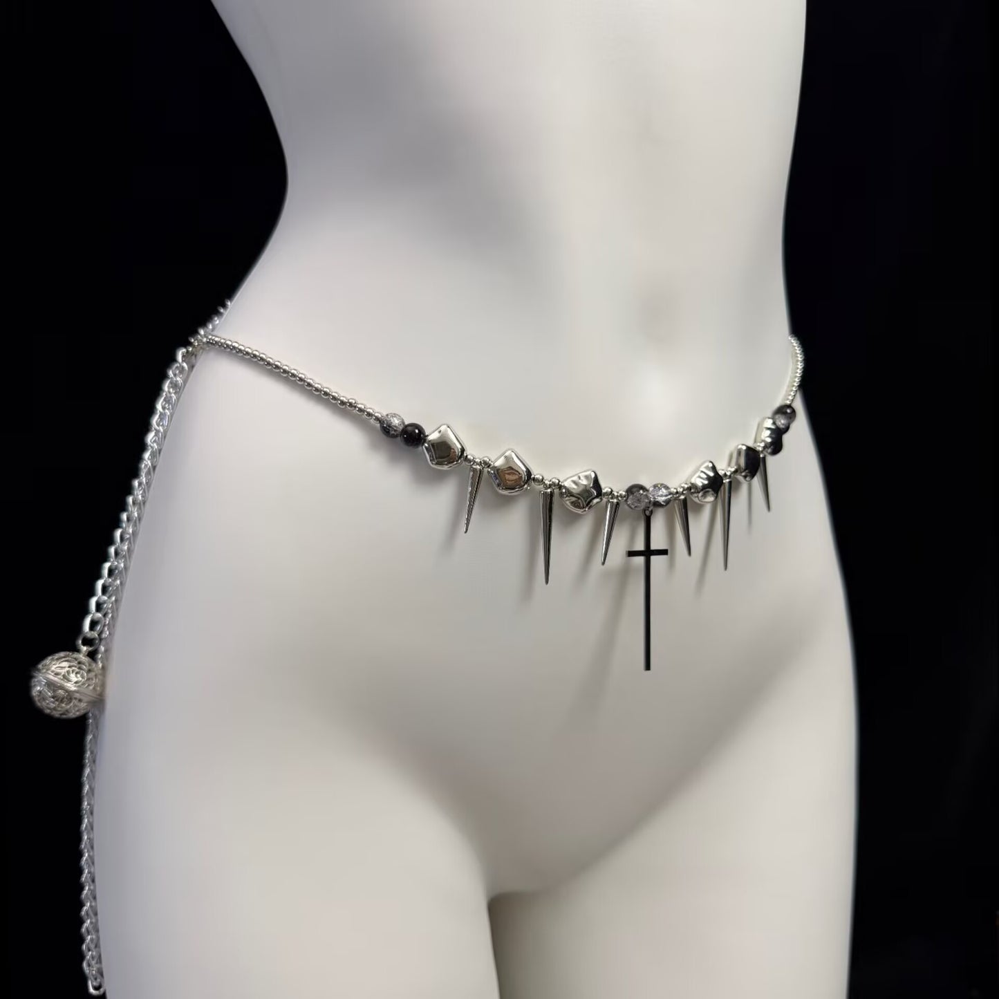 Detailed view of a gothic waist chain featuring metallic spikes, black beads, and a central cross pendant.