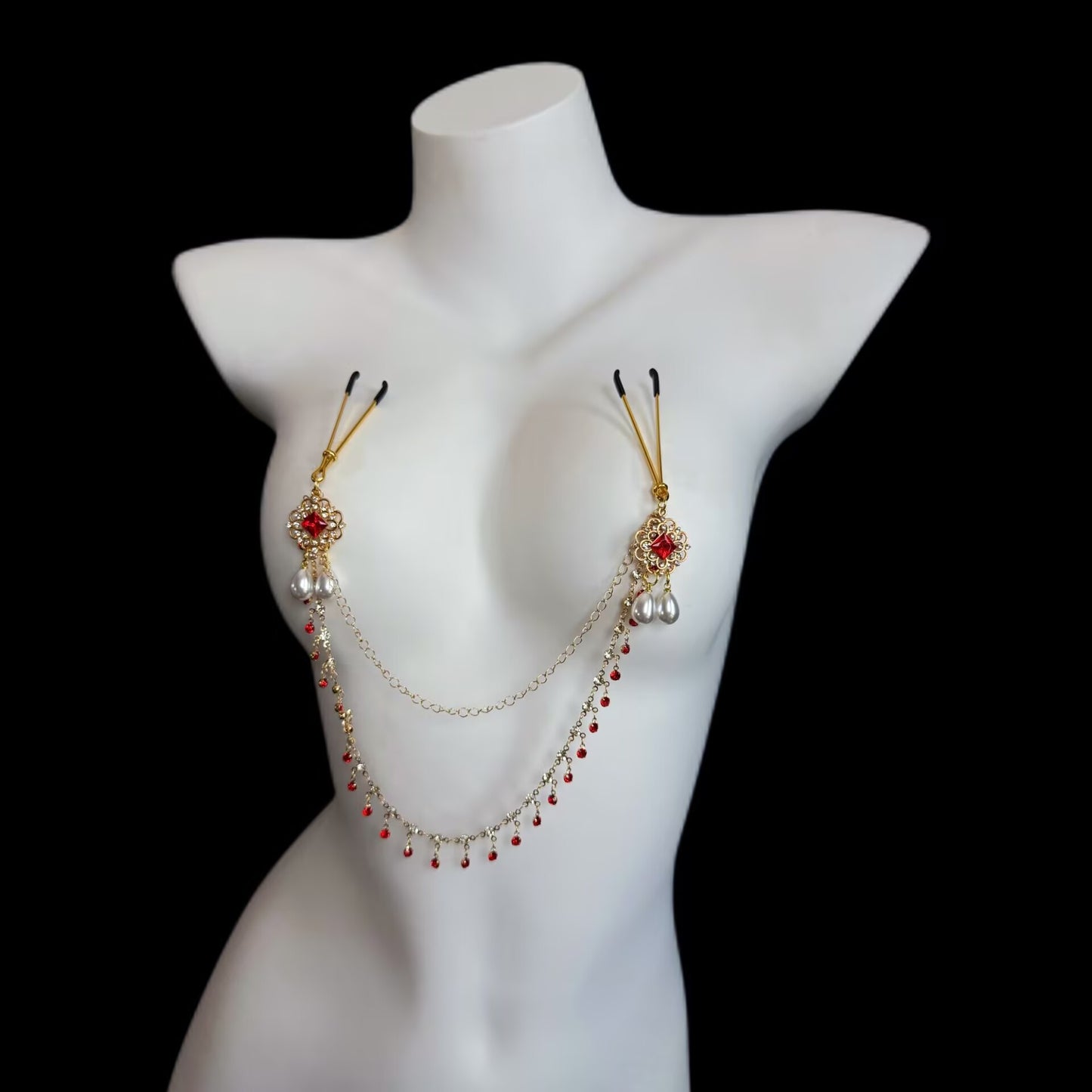 Angled view of gothic style breast chain accessory with non-pierced rubber grips, red gem flowers, and pearl drop tassels on mannequin.