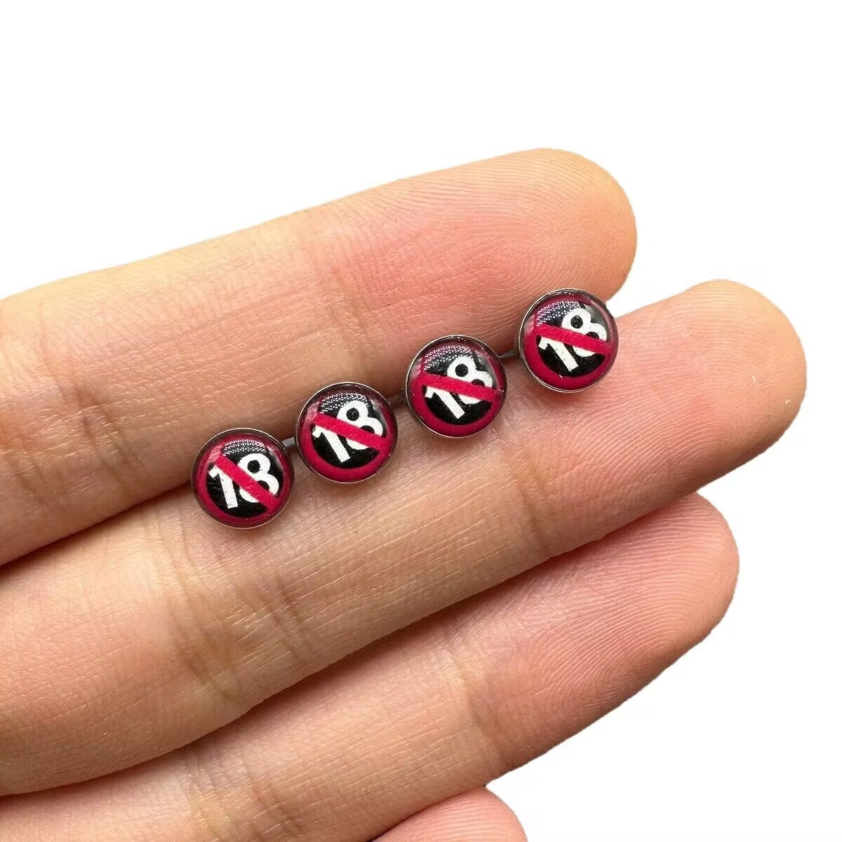Hand holding a row of 18 restricted graphic tongue barbells showing top disc detail.