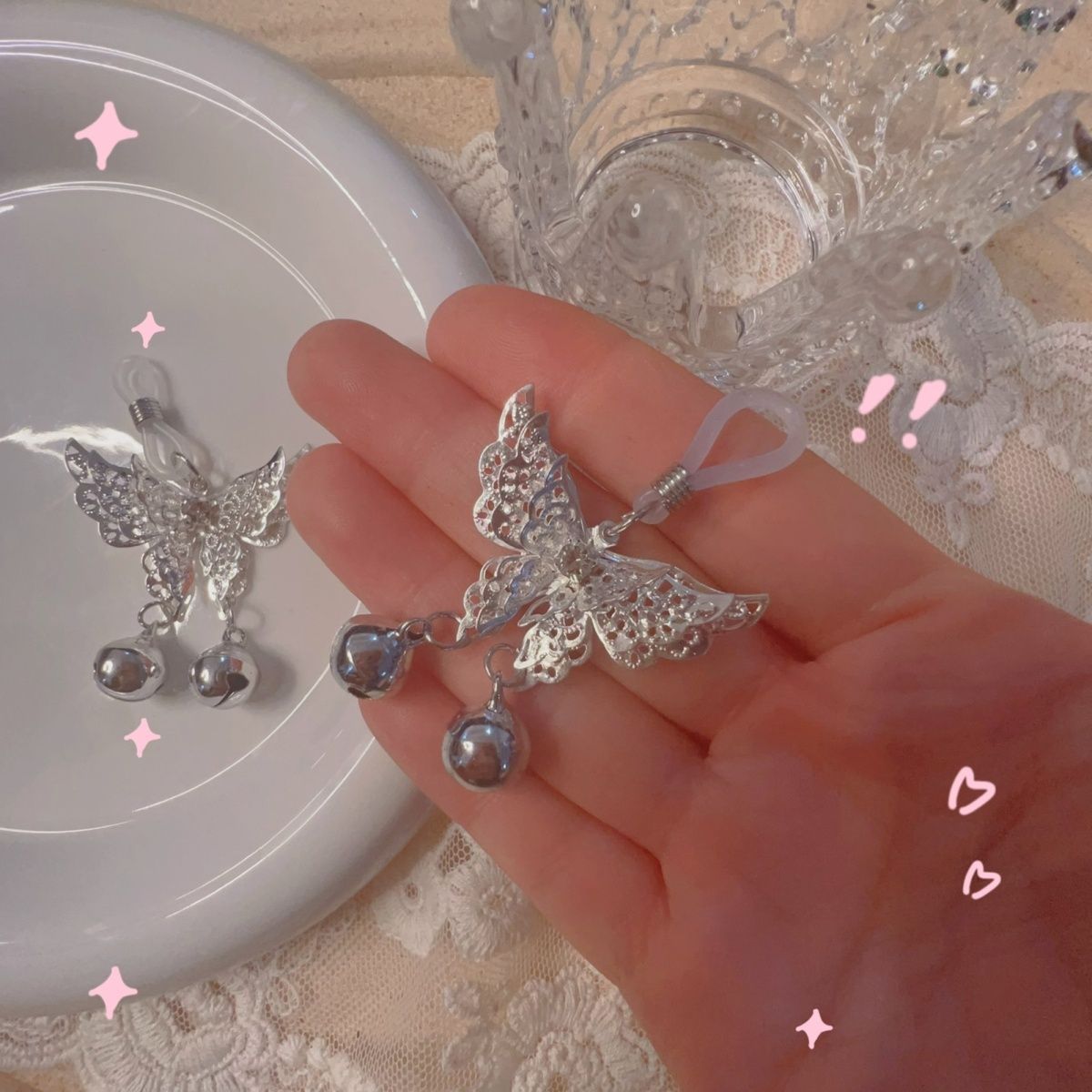 A hand holding the adjustable butterfly nipple clamp to demonstrate size and the clear silicone loop.