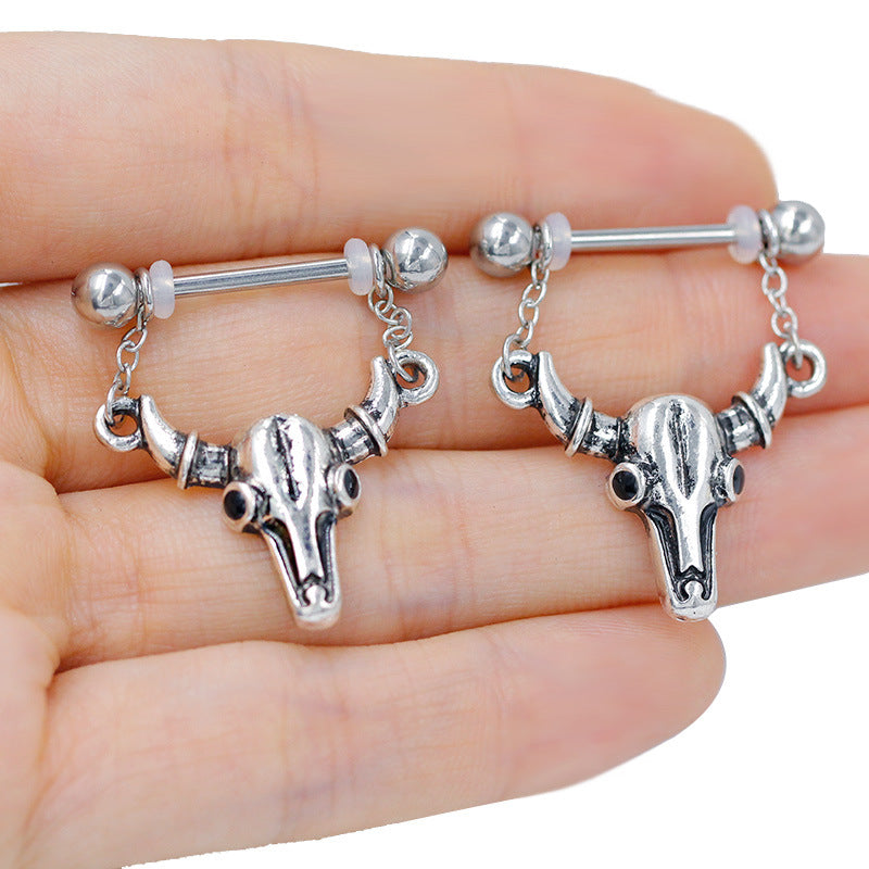 Close-up of a person holding two cow skull nipple piercings to show scale and intricate metal details