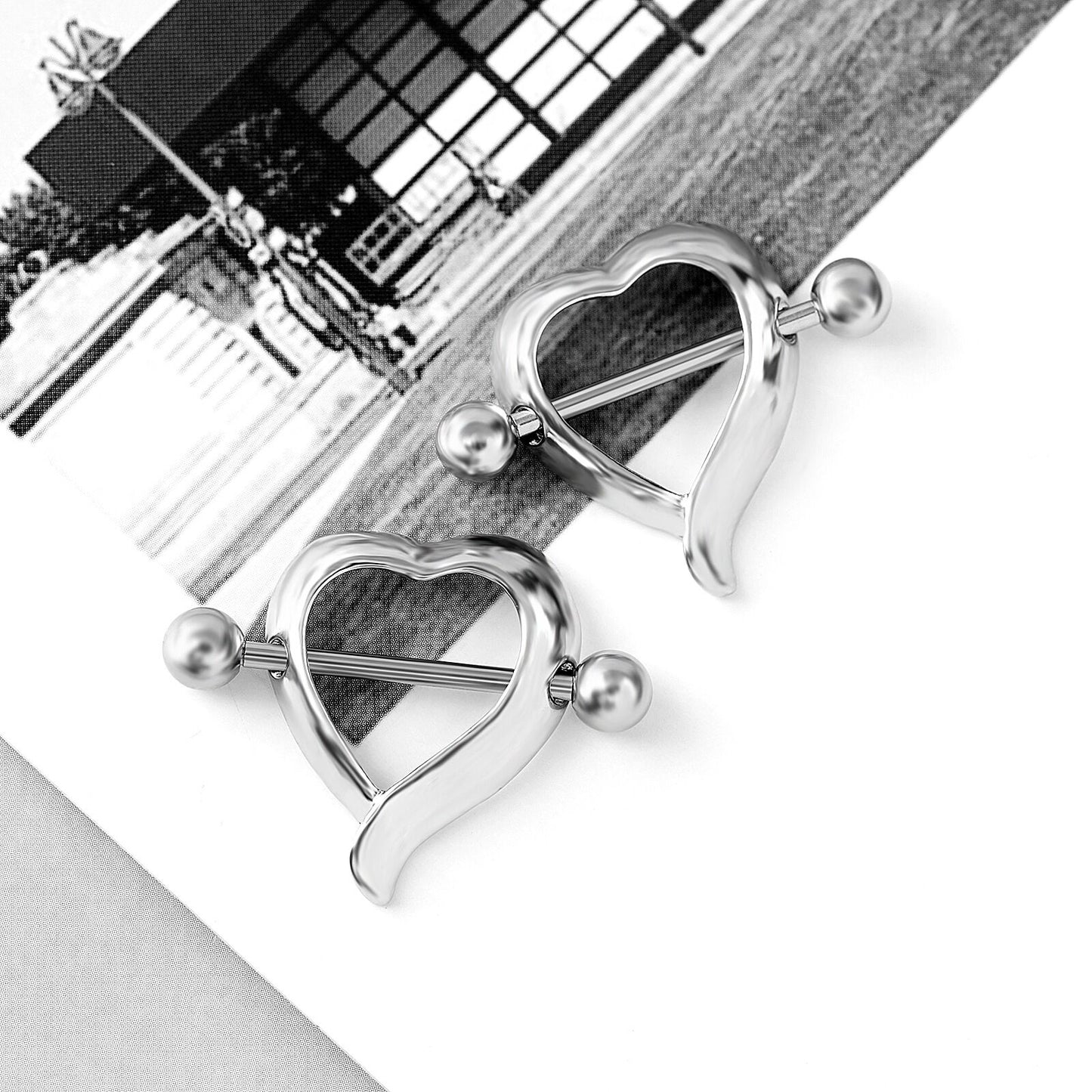 Two heart-frame nipple shields placed on a clean white surface with an artistic background.