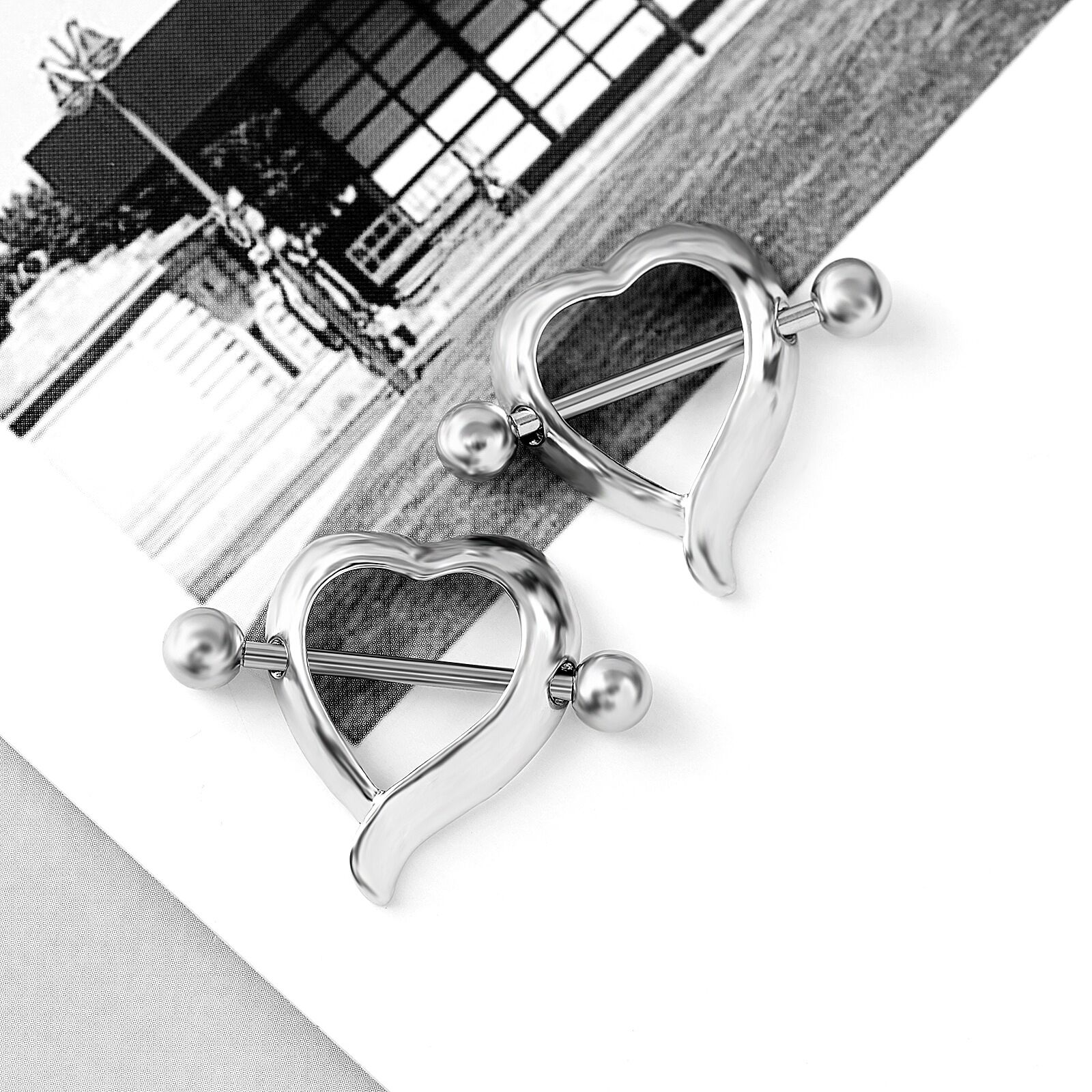 Two heart-frame nipple shields placed on a clean white surface with an artistic background.