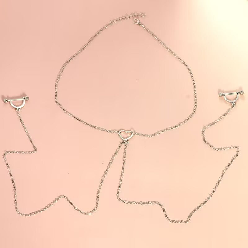 Flat lay product photography of a minimalist silver hollow heart necklace body chain connected to a pair of sleek U-shaped arc nipple rings.