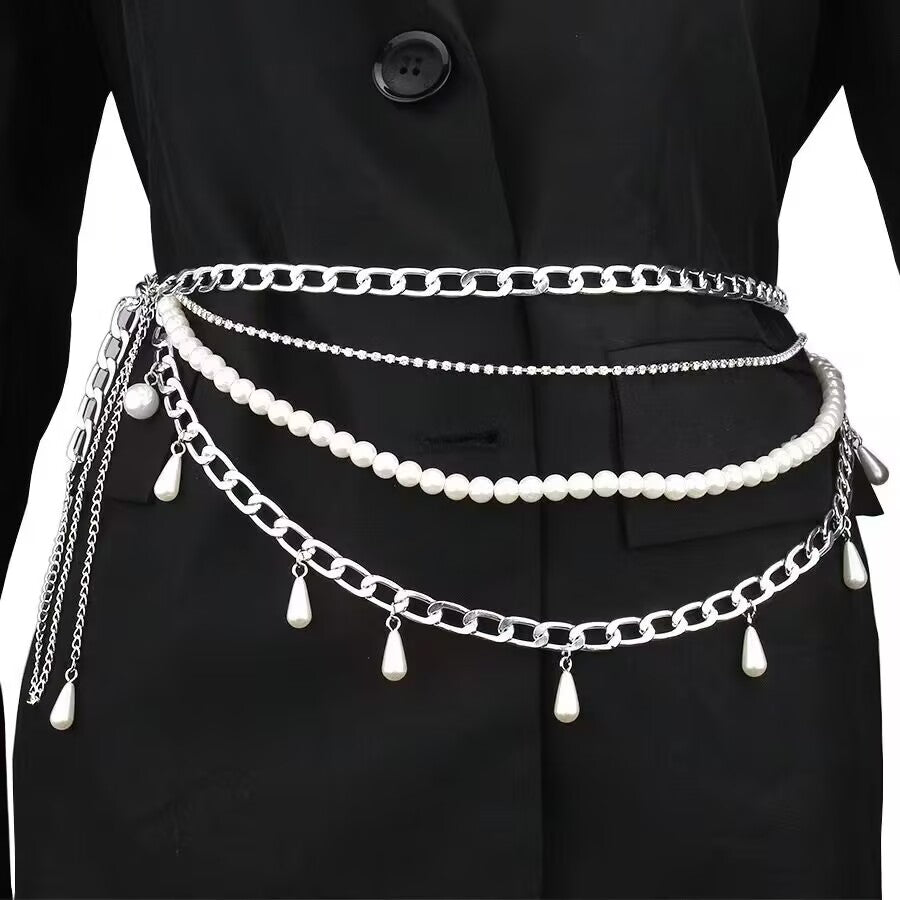 Close up of a silver multi layer body waist chain with chunky link chain, rhinestone strand, and a layer of round pearls with hanging teardrop pearl charms worn over a black blazer jacket.
