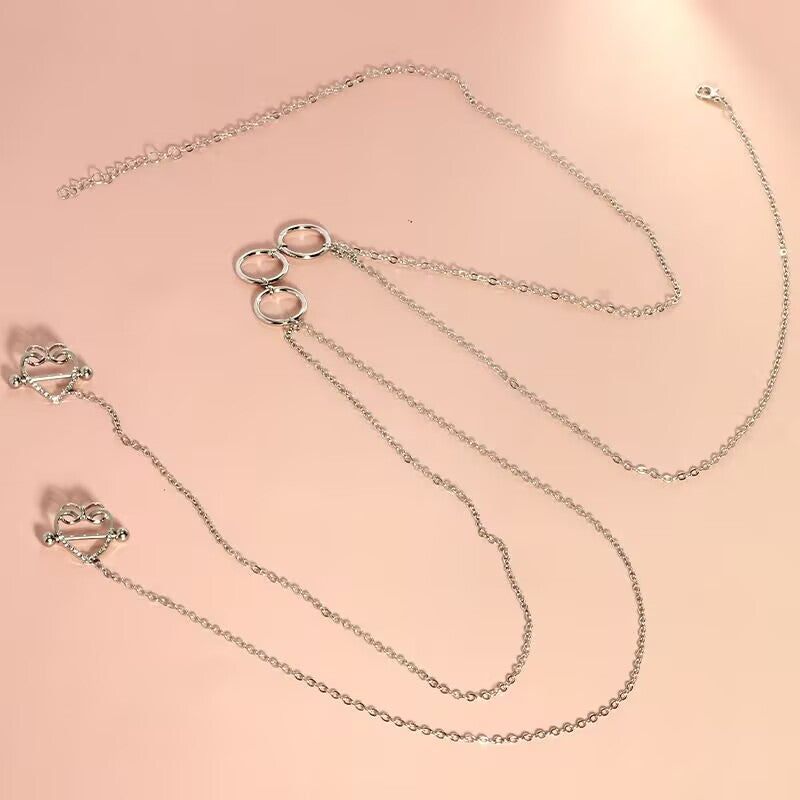 Top-down view of the silver interlocking 3-ring choker body jewelry with two crystal heart nipple pierces, showcasing chain lengths and lobster clasps.