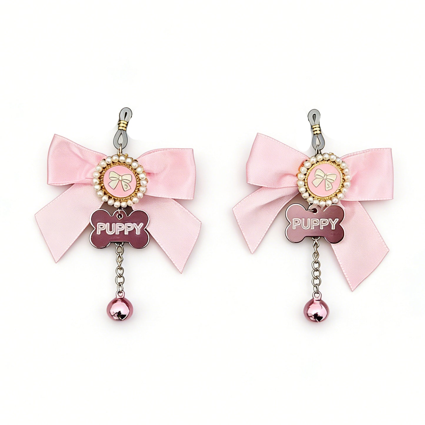 A pair of pink satin bow nipple jewelry featuring "PUPPY" bone tags and tinkling bells.