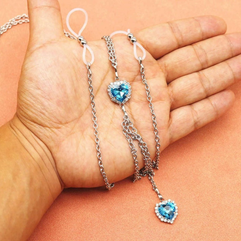 Lake blue heart nipple chain resting across a hand, showing two silicone loops and both heart pendants