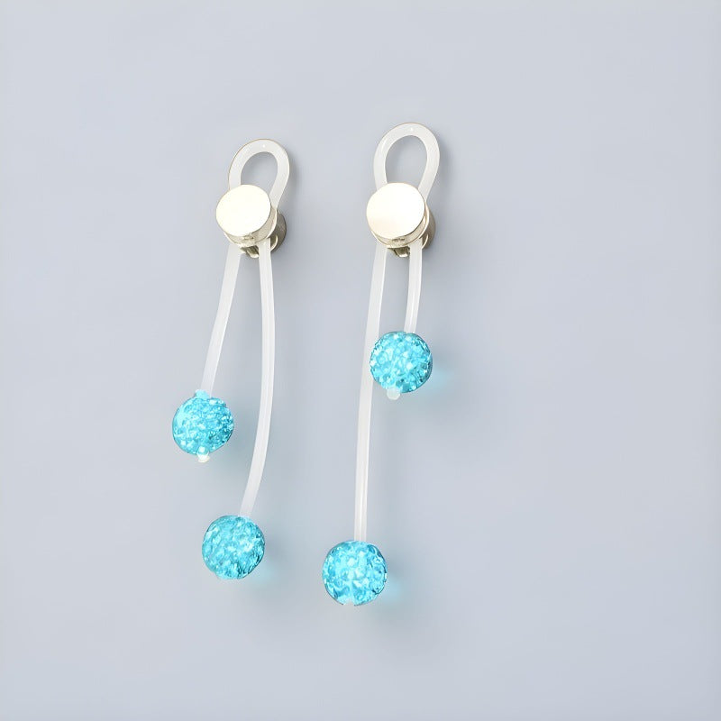 Pair of lake-blue non-piercing nipple clips with translucent straps and four sparkling blue bead drops on gray.