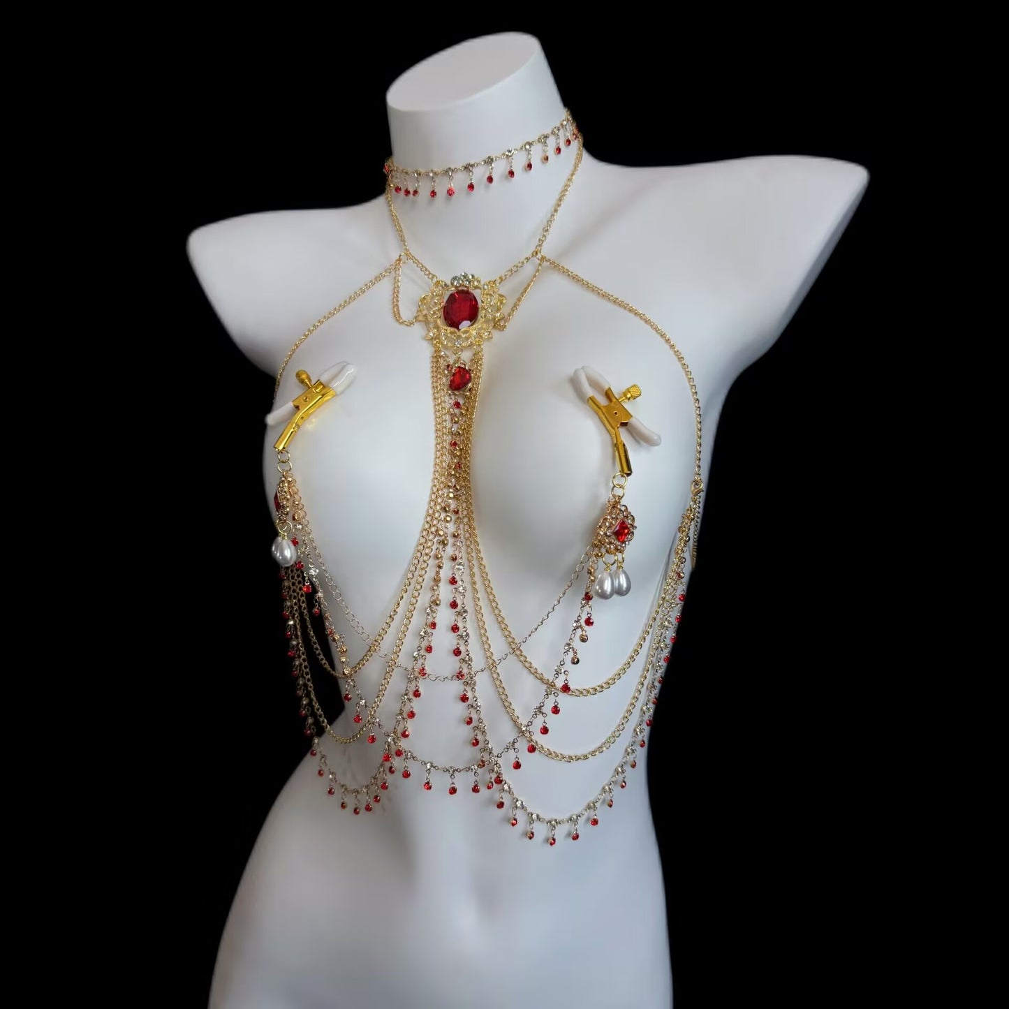 Layered gold-tone chest body chain combined with non-pierced adjustable screw breast clamps decorated with ruby crystal medallions and pearl tassels.