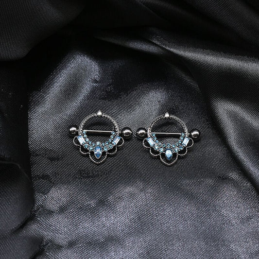 Two blue crystal crown nipple rings displayed on elegant black silk fabric for a luxury look.