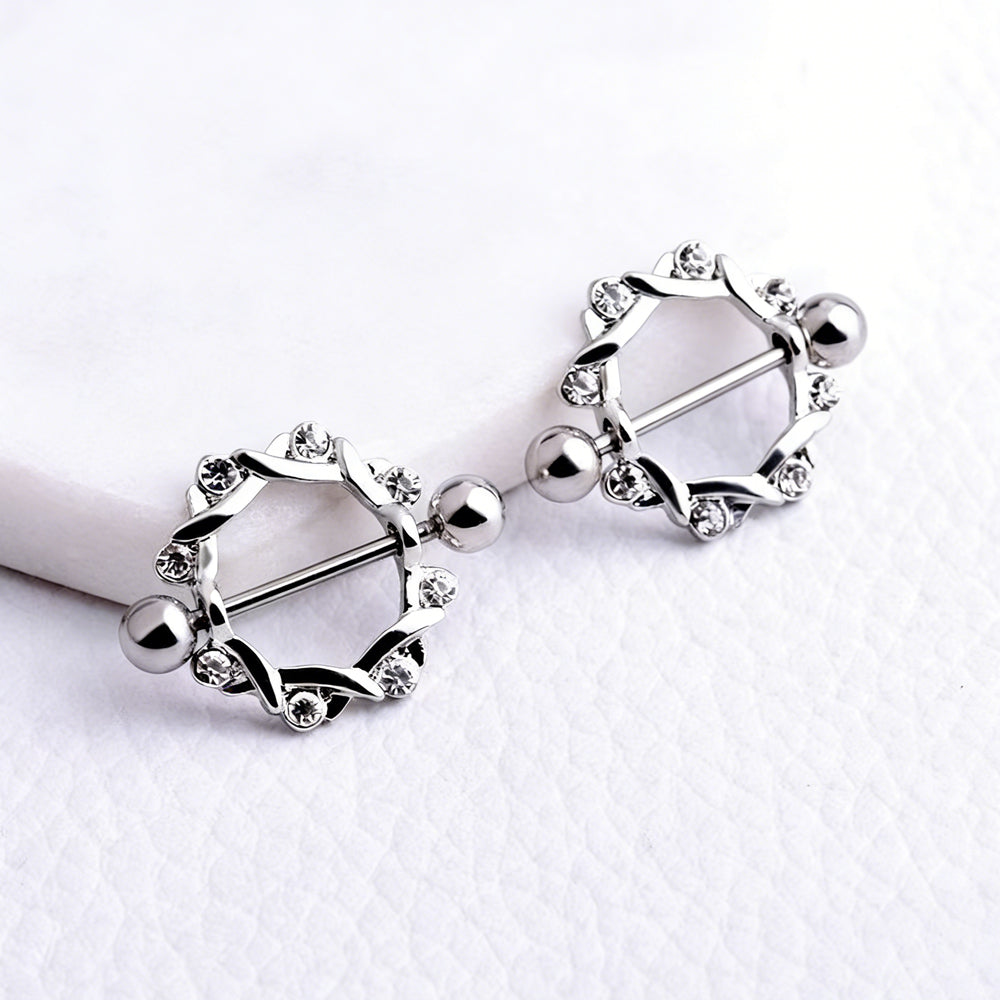 Close-up lifestyle photography of two vine-style nipple shields resting on a textured white surface.