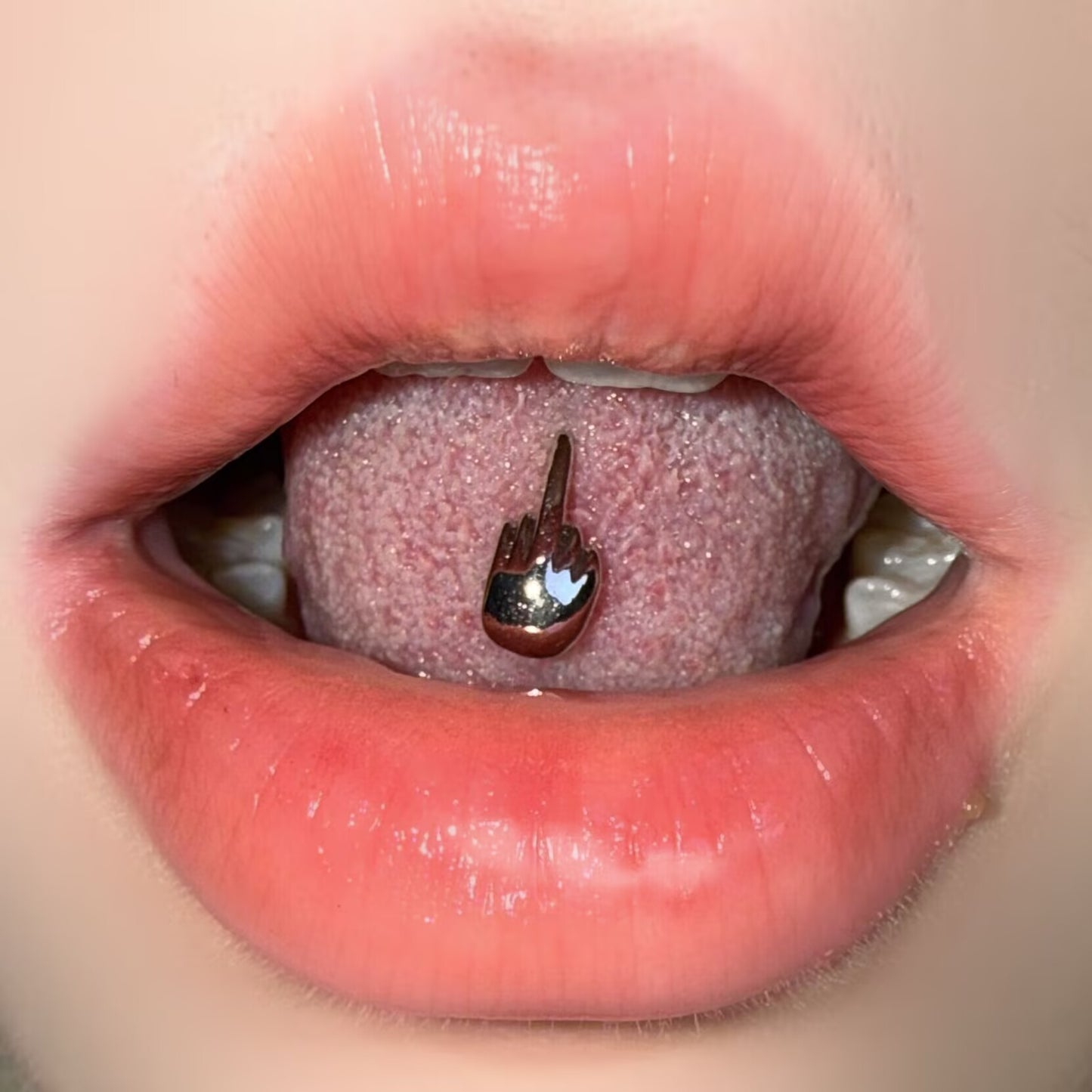 Middle finger tongue ring worn inside mouth as a statement body piercing jewelry.