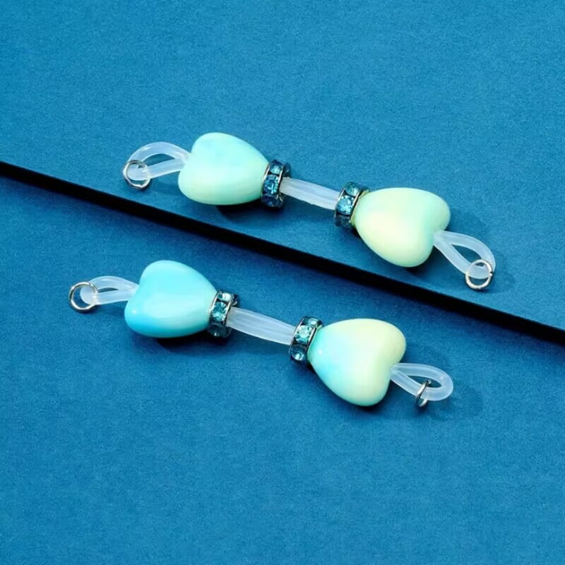 Pair of mint green heart soft silicone fake nipple rings featuring blue rhinestone spacers for comfortable non-piercing wear.