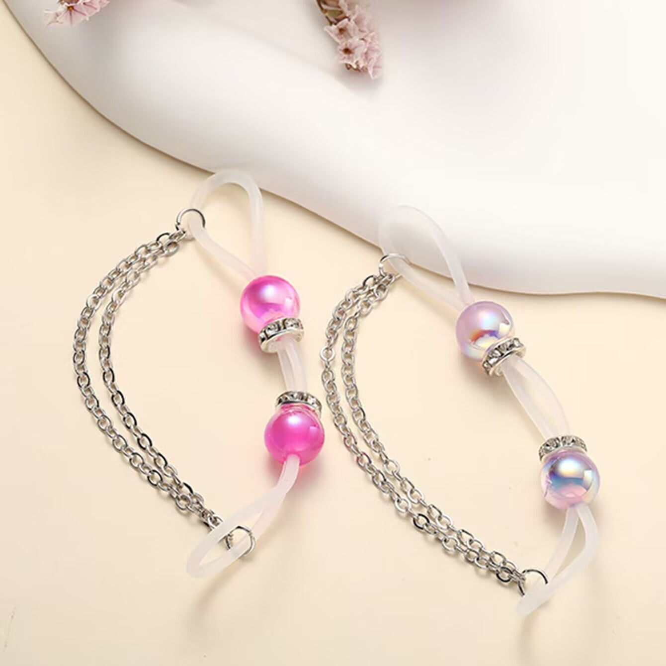 Lifestyle shot of pink and white iridescent non-pierced nipple rings with flexible loops and chains.