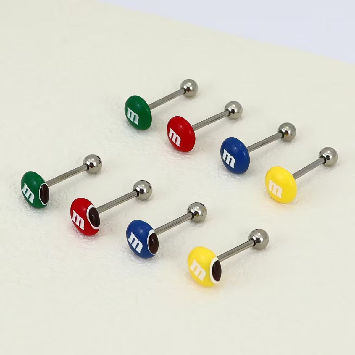 Side view of M&M style tongue barbells highlighting threaded ball backs and smooth m-logo candy ends.