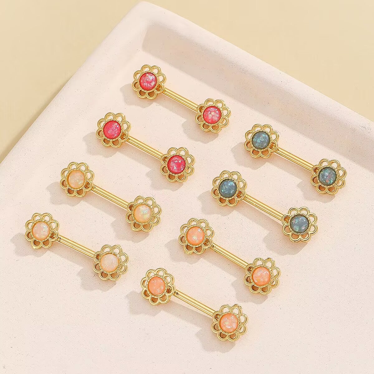 A collection of non-pierced floral nipple rings in various colors including pink, white, peach, and teal.