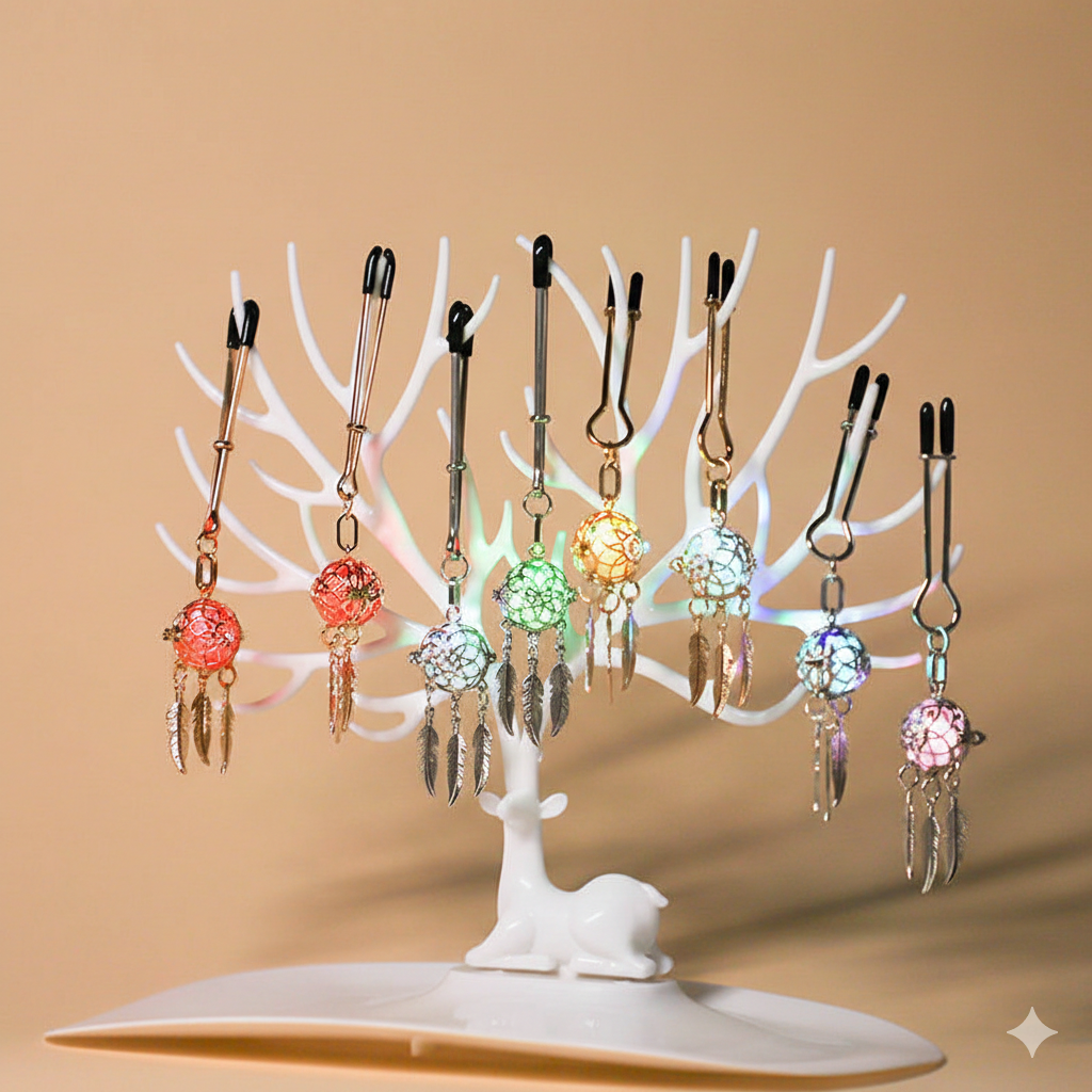 Display of dreamcatcher nipple clamps glowing in multiple LED colors on a jewelry stand